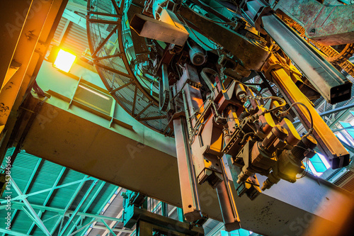 Industrial travelling crane at aluminium plant interior.