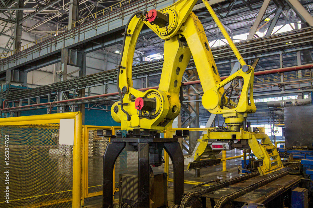 Yellow loader unloader robot at conveyor working area.