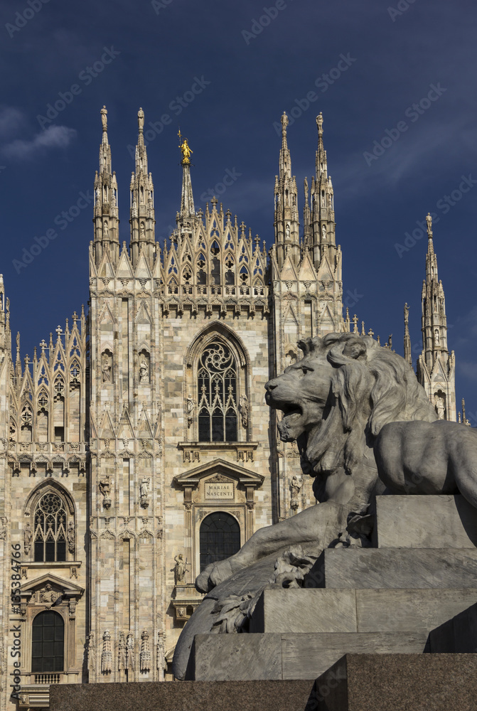A lion figure on a side of Vittorio Emanuele II equestrian statue pedestal in front of Duomo (Cathedral) on Piazza del Duomo of Milan, Italy