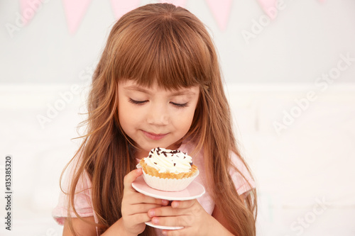 Cute birthday girl eating tasty cake at home