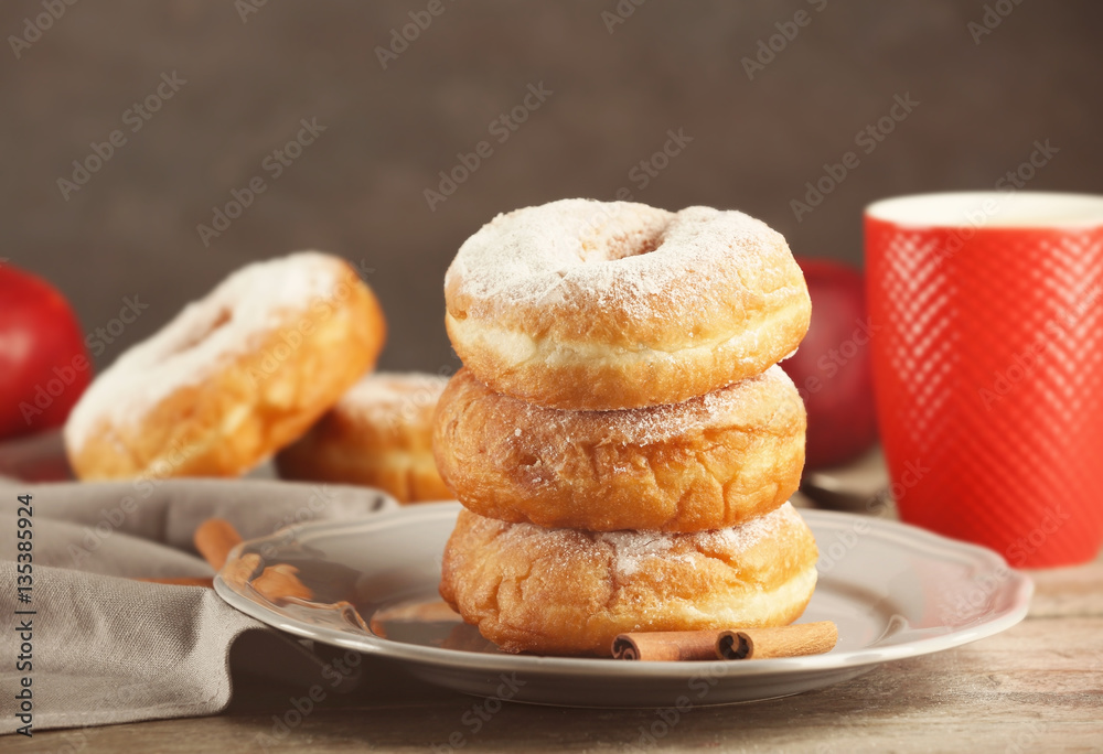 Plate with delicious doughnuts on table