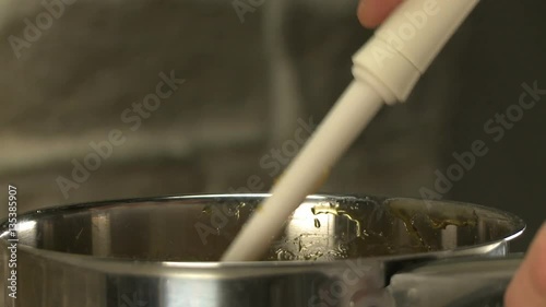 Cooker stirring syrop in bowl with kitchen spatula photo