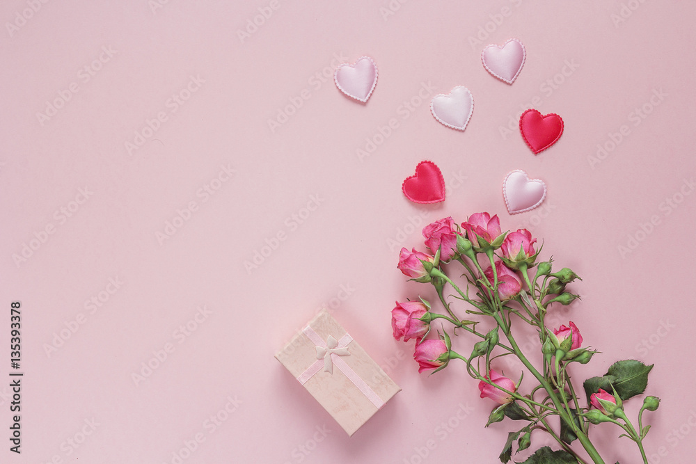 Bouquet of roses, gift box and hearts on a pink background. Spac
