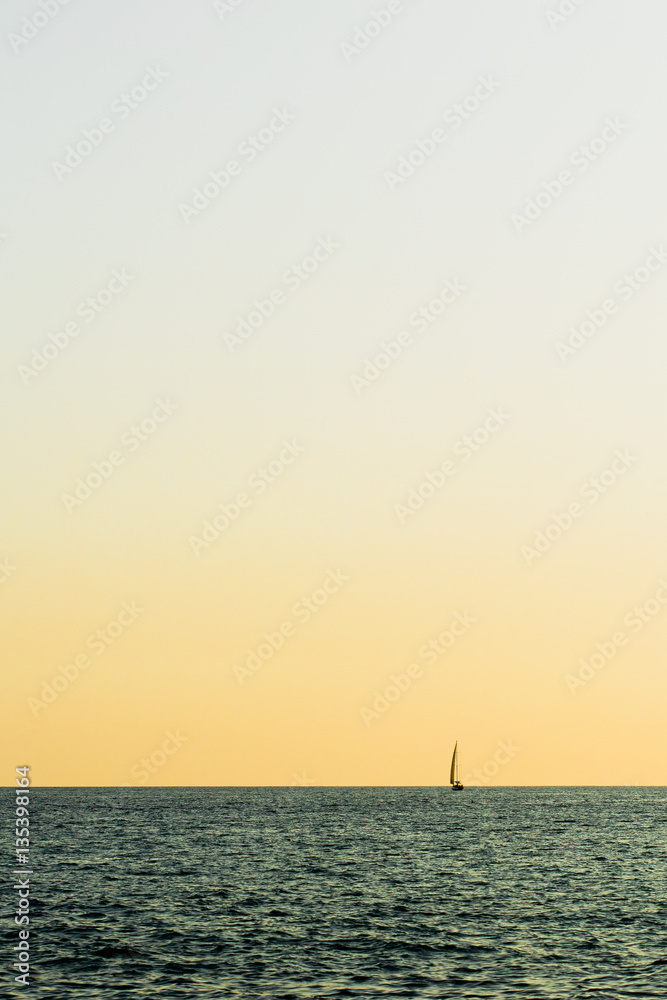 alone sailboat in the sea on sunset