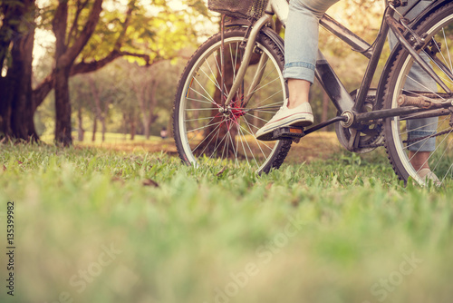 Close up Young woman riding bike, blurred grass foreground. 