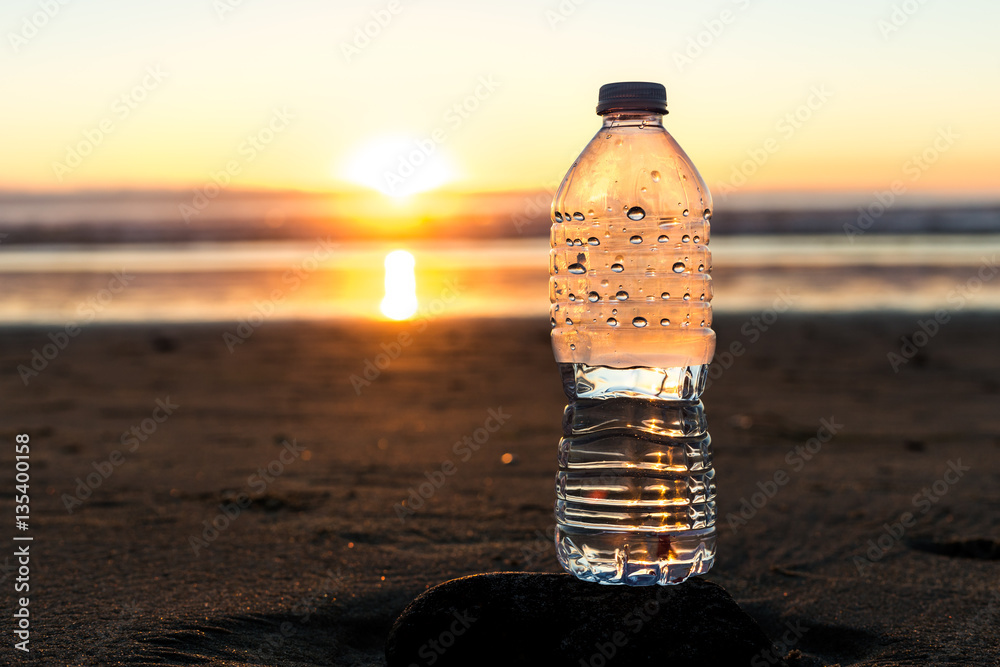 Plastic bottle of water on the beach at sunset , sunrise time Stock Photo