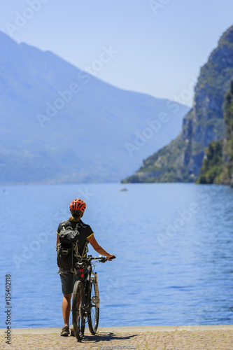 Mountain biking at sunrise woman over Lake Garda on path