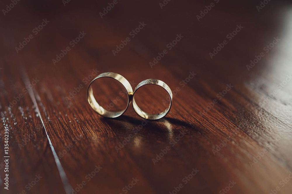 beautiful gold wedding rings lying on wooden surface