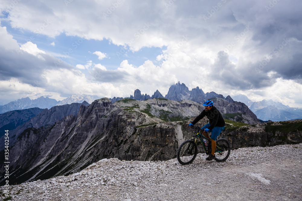 View of cyclist riding mountain bike on trail in Dolomites,Tre C View of cyclist riding mountain bike on trail in Dolomites,Tre C