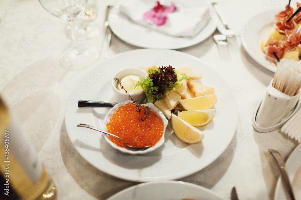 Red caviar and slices of lemon on white tray Red caviar and slices of lemon on white tray