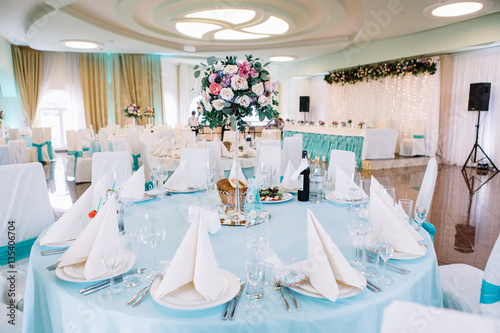 White plates with beige serviettes on them stand on blue dinner photo