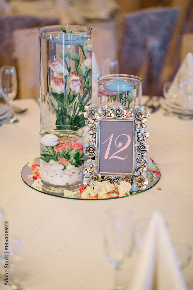 Frame with number 12 stands on mirror tray with flowers Frame with number 12 stands on mirror tray with flowers