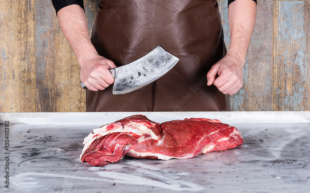 hand butcher cuts a large piece of meat