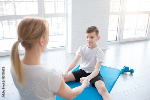 Women with little boy doing stretching workout on fitness mat
