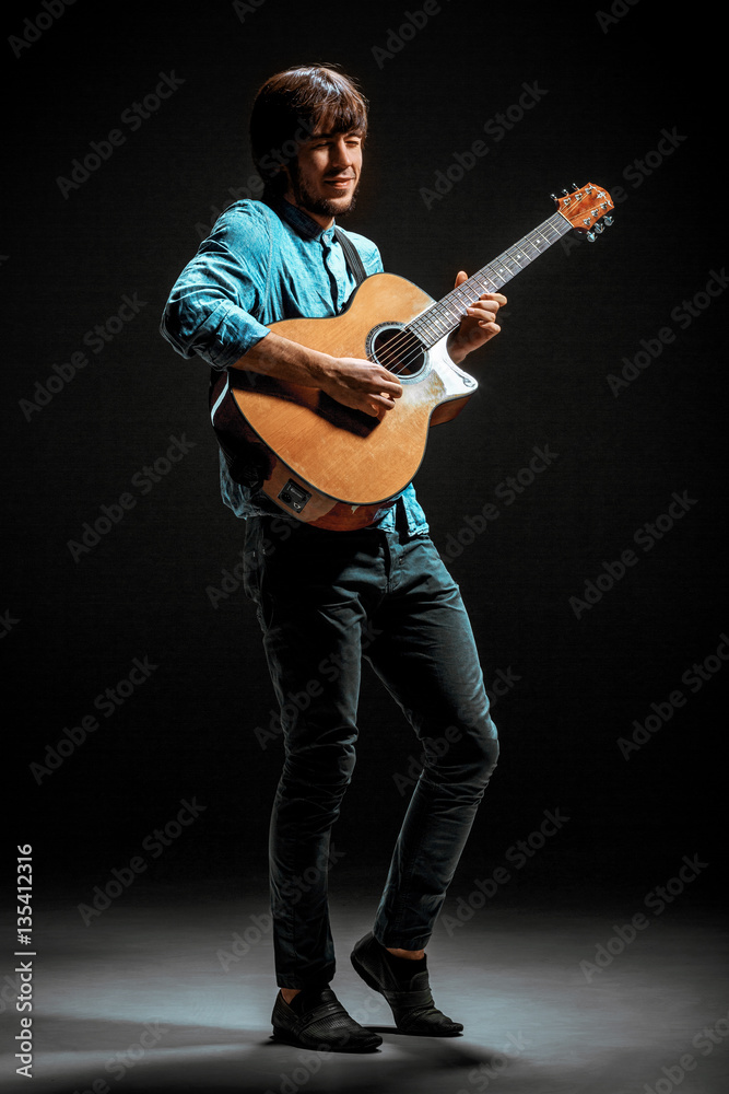 Cool guy standing with guitar on dark background Cool guy standing with guitar on dark background