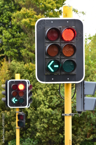 Traffic lights on yellow metal poles operating during daytime.