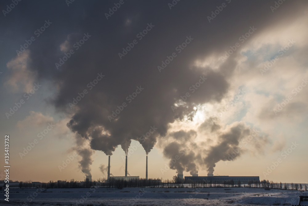 Silhouette of power plant with gray smoke