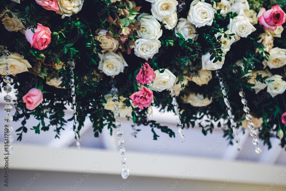 Sparkling crystal chains hang from garland of pink and white ros