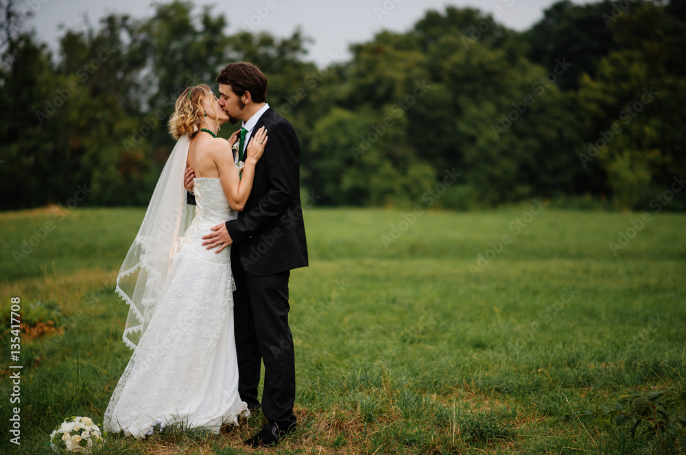 Embracing wedding couple in love on cloudy weather outdoor.