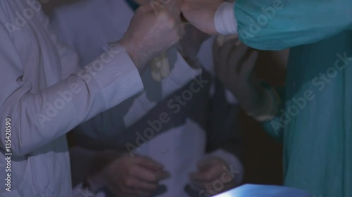 A nurse in a military hospital helps the surgeon to wear gloves photo