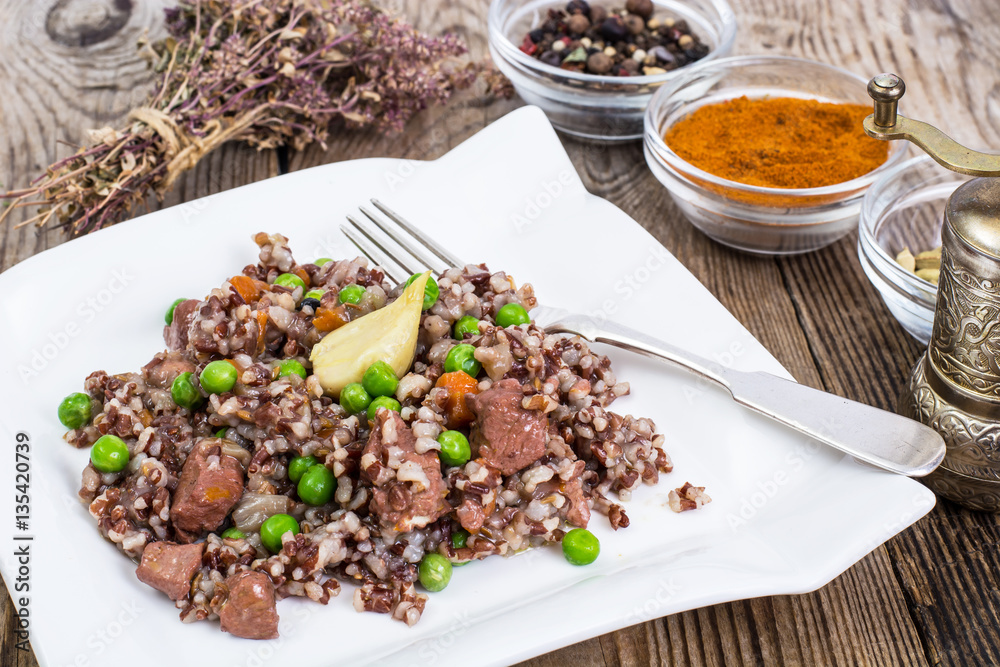 Boiled red rice with vegetables and slices of chicken on a woode