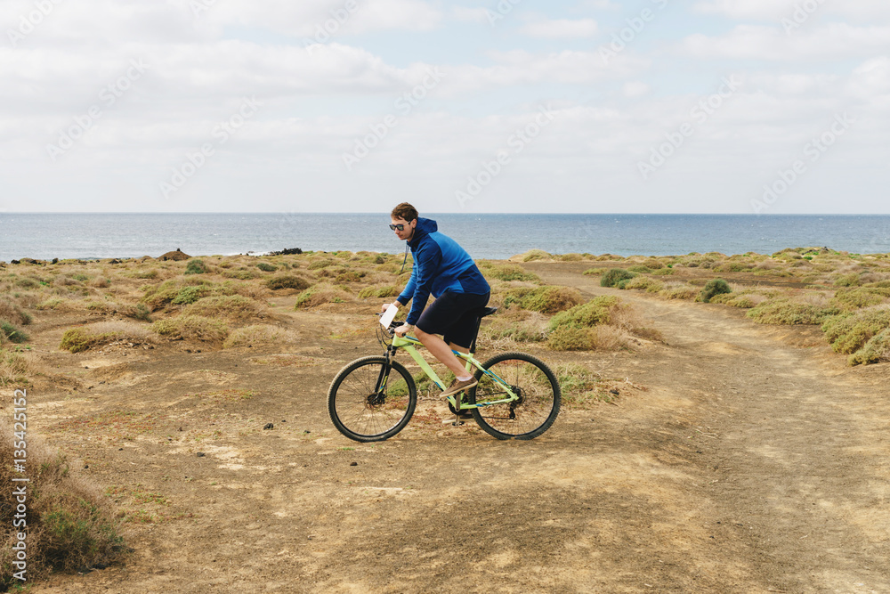 handsome man  in casual outfit ride a mountain bike on island