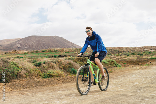 handsome man in casual outfit ride a mountain bike in mountains