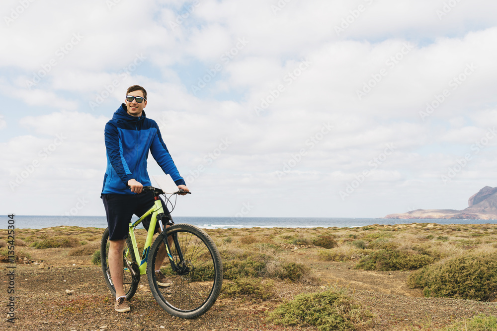 handsome man in casual outfit ride a mountain bike on island handsome man in casual outfit ride a mountain bike on island