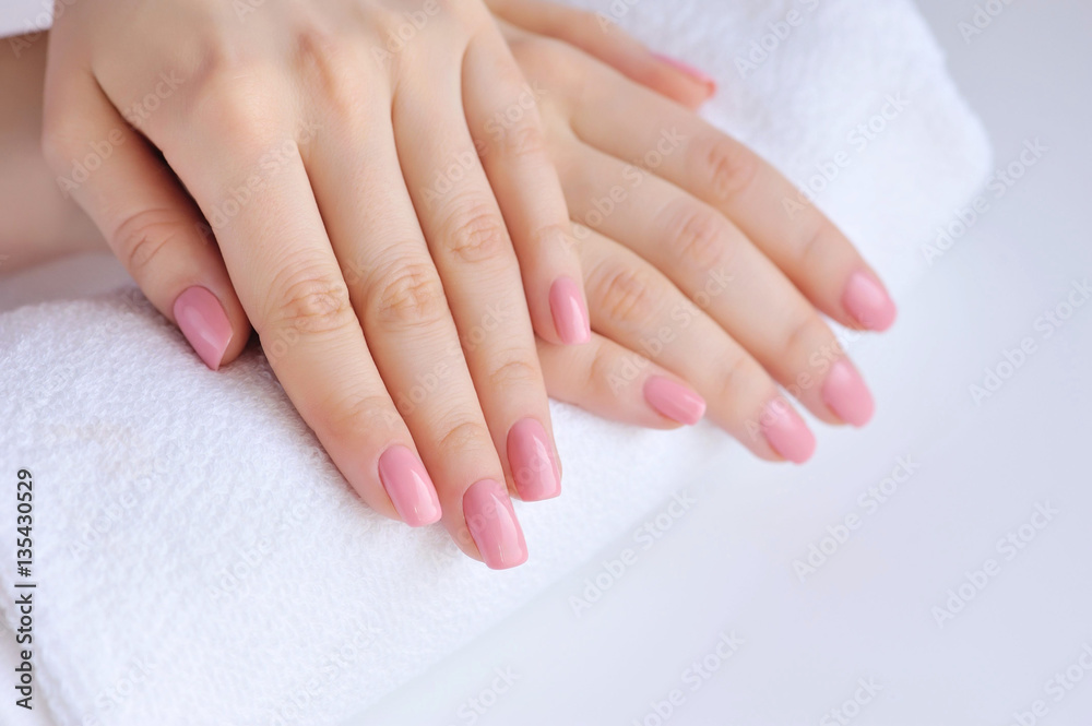 Hands of a woman with pink manicure are on a towel