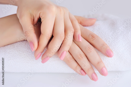 Hands of a woman with pink manicure are on a towel