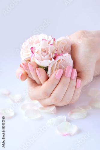 Sticker Hands of a woman with pink manicure on nails and roses against white background