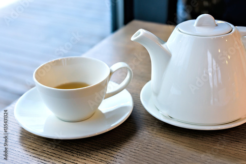 Cup of tea and teapot on a wood table in the restaurant
