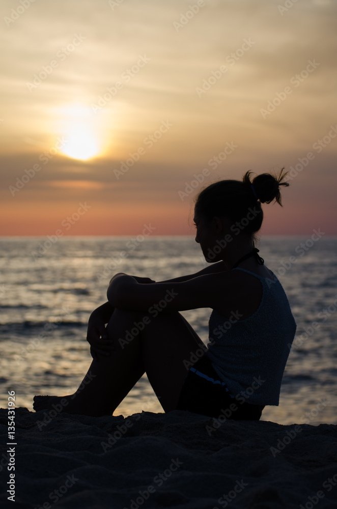Silhouette of girl on the seashore at sunset.