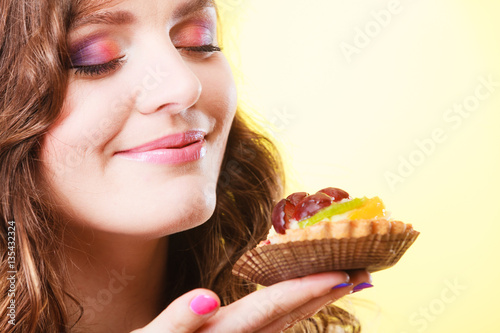 woman closed eyes holds cake in hand