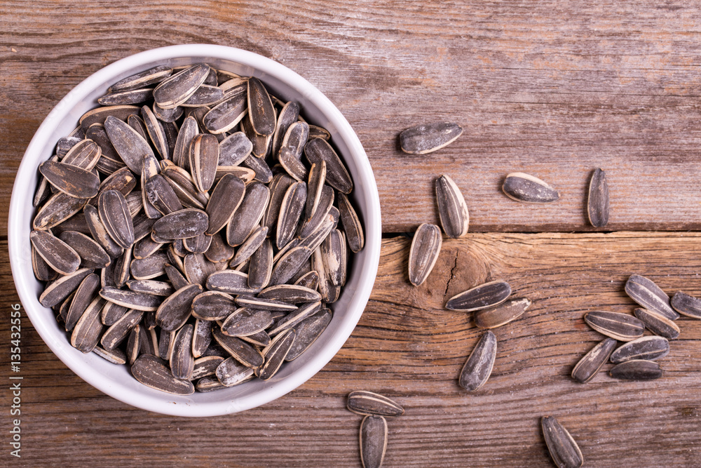 Sunflower seeds in white ceramic bowl. Top view. 