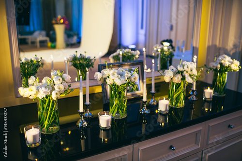 The vases with flowers and candles stand on the commode