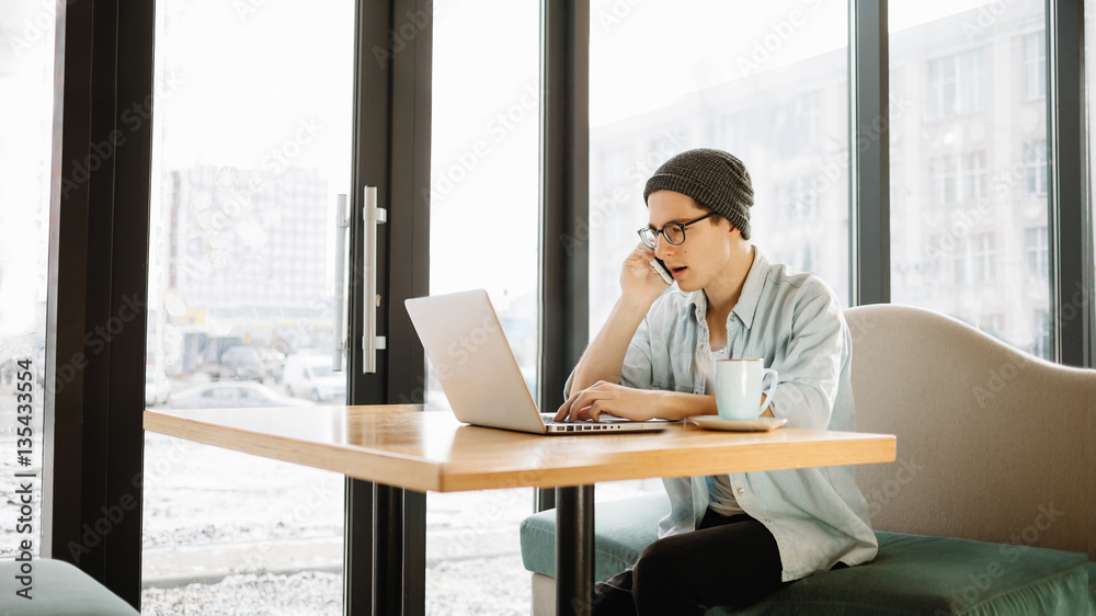 Handsome businessman in casual wear and eyeglasses is using a laptop in cafe Handsome businessman in casual wear and eyeglasses is using a laptop in cafe