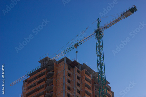 Crane and building construction site against blue sky © Aleksandr Murzich