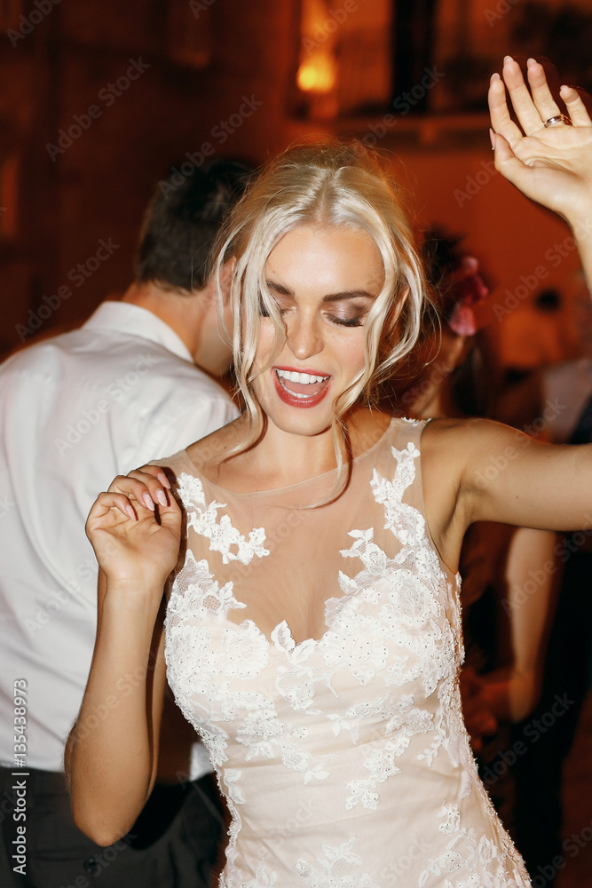 Fototapeta premium Stunning blonde bride dances raising her hands up