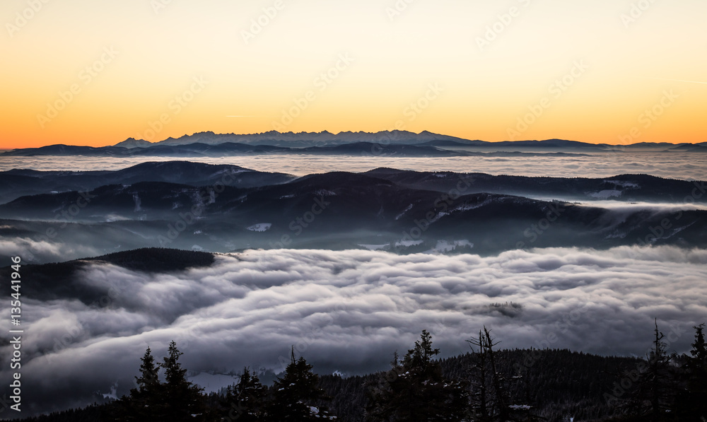 high mountains silhouette in the winter morning before sunrise above the clouds