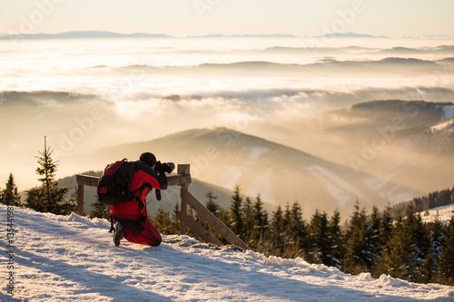 hobby photographer taking photos in cold mountains with epic morning sunlit scenery 