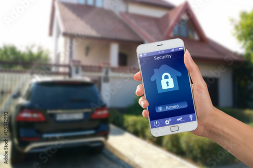 Smartphone with home security app in a hand on the building background