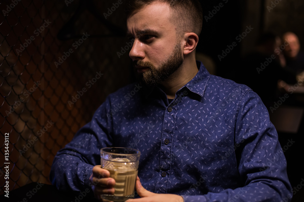 Business man, in blue shirt and glasses, drinking cocktail of vintage old fashion glass in loft bar Business man, in blue shirt and glasses, drinking cocktail of vintage old fashion glass in loft bar