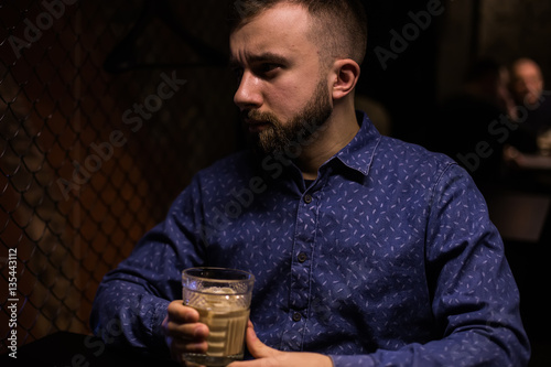 Business man, in blue shirt and glasses, drinking cocktail of vintage old fashion glass in loft bar