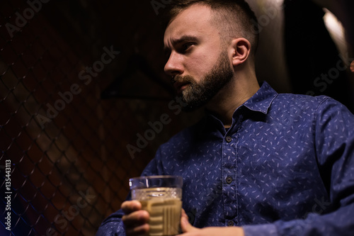 Business man, in blue shirt and glasses, drinking cocktail of vintage old fashion glass in loft bar