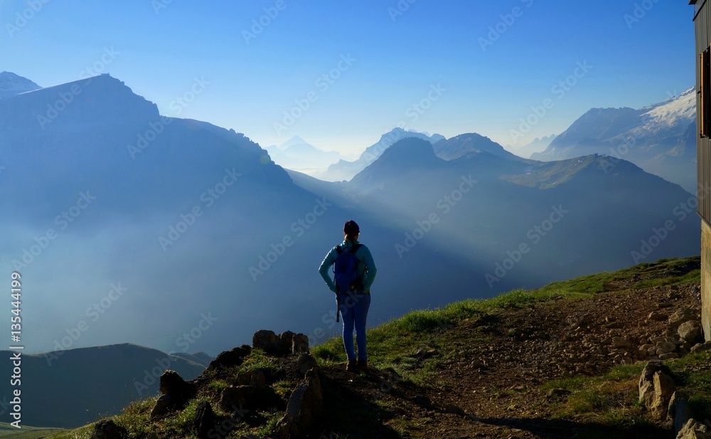 Wanderin genießt in Morgensonnen Aussicht auf Südtiroler Gebirgslandschaft / Sella & Marmolada