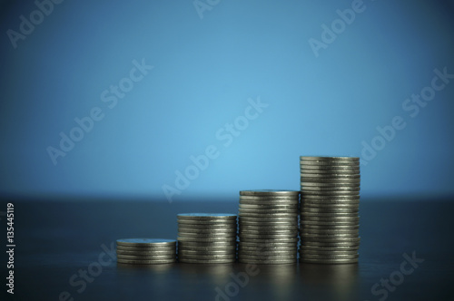 pile of coins, money on dark wood and soft blue background