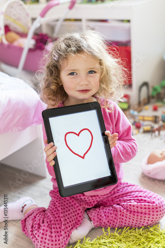 Little girl drawing a Heart on her Tablet pc