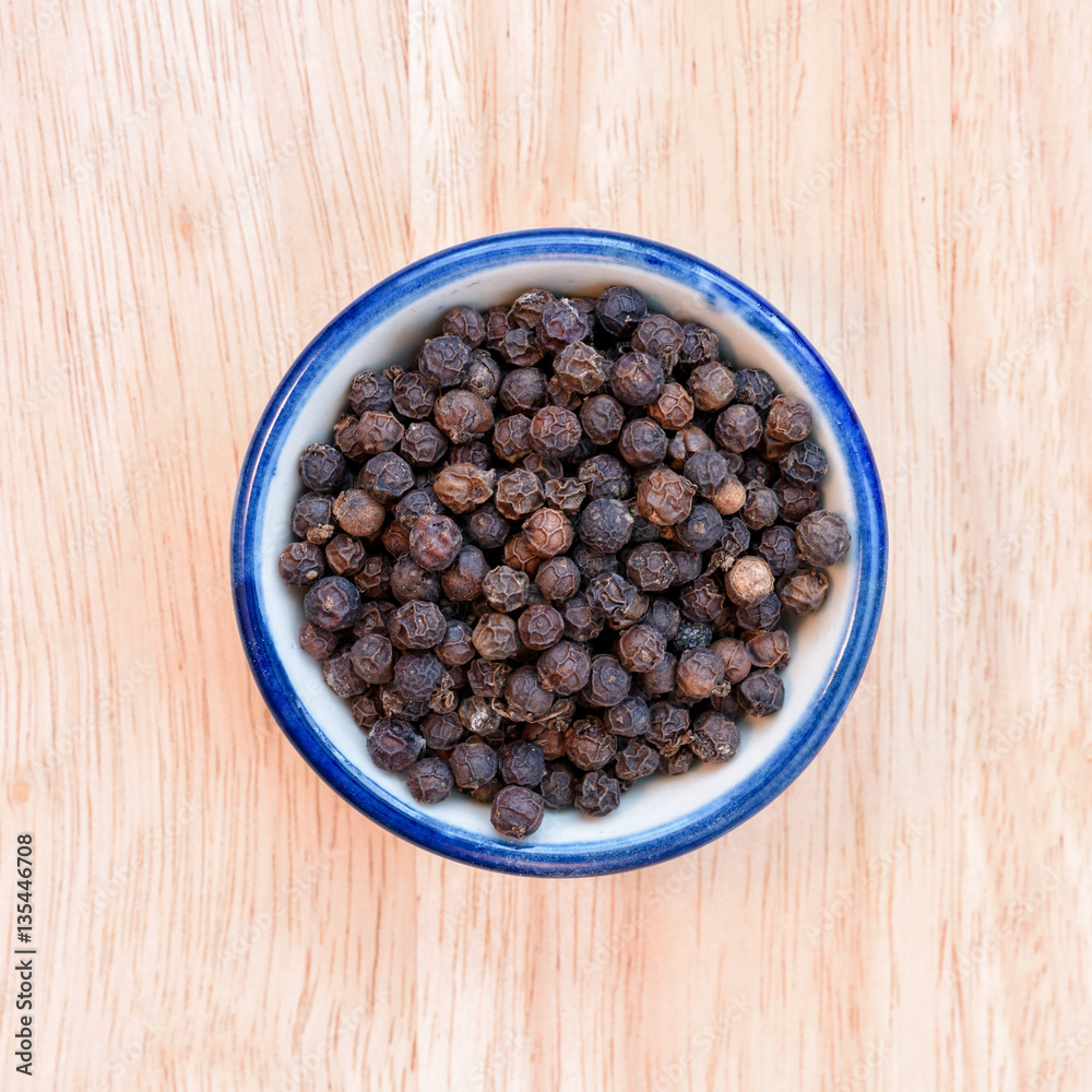 Black pepper in bowl on wood floor background. Black pepper in bowl on wood floor background.