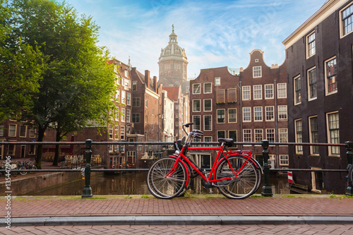 Houses and Boats on Amsterdam Canal. Morning photo of colored houses in the Dutch style and bridge with a red bicycle in the foreground